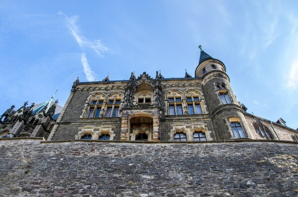 Un edificio histórico con una torre destacada, ventanas de arco y detallada ornamentación de piedra.