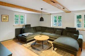 A modern living room with a sectional sofa, a round coffee table, and a pendant light.