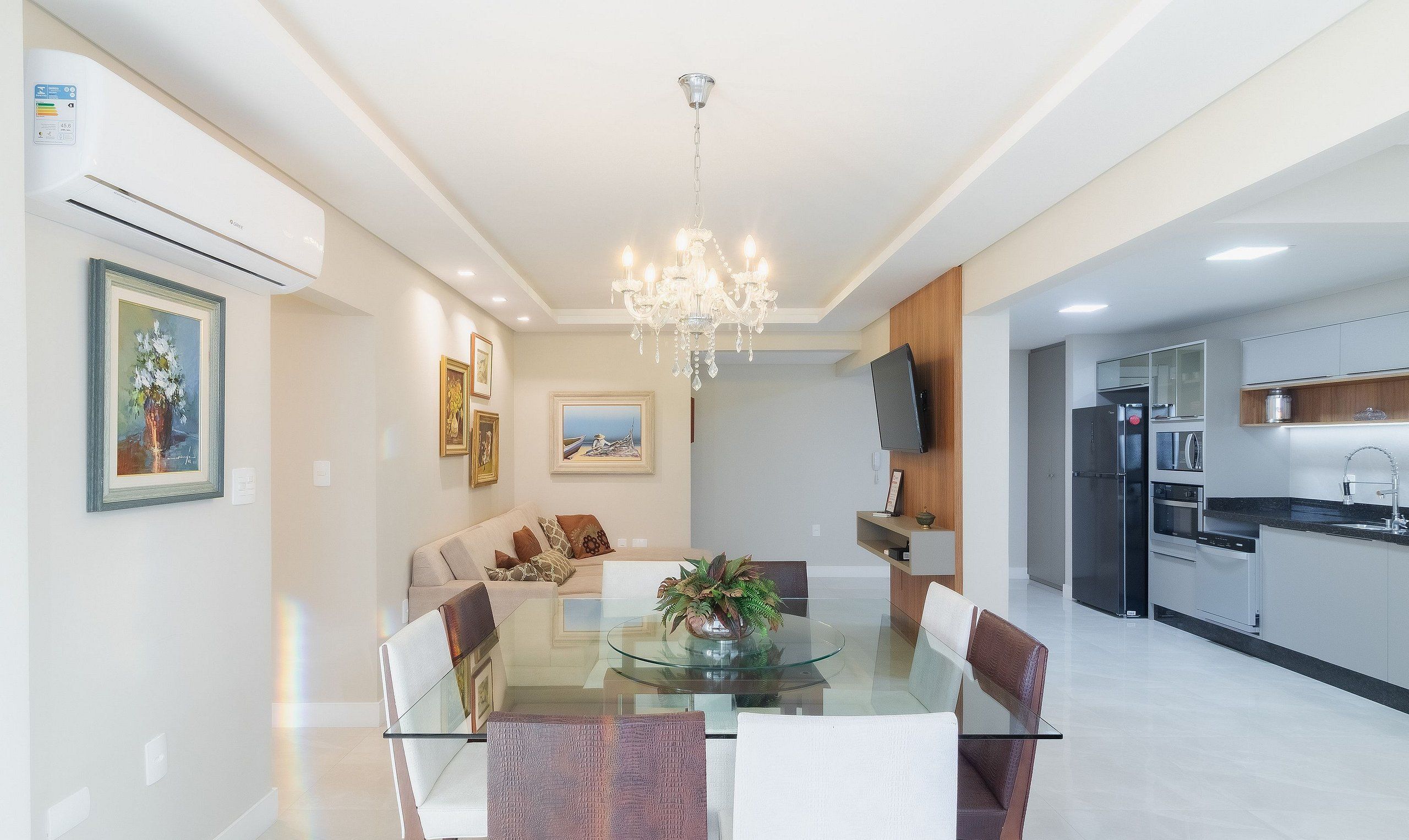 A modern dining area with a glass table, cushioned chairs, and a chandelier.