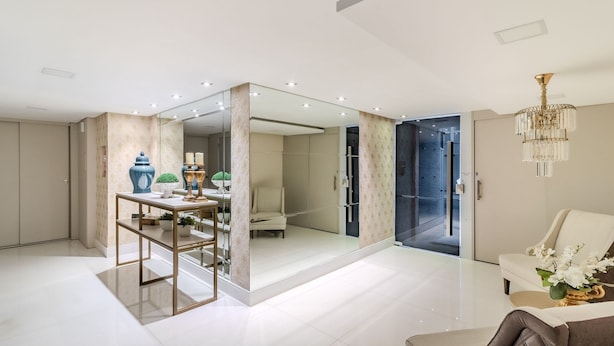 A modern bathroom with a glass shower enclosure, a vanity with a mirror, and a chandelier.