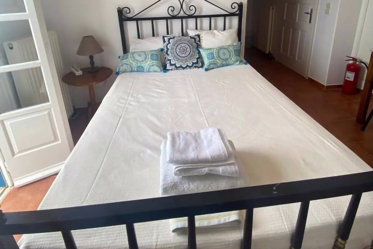 A bedroom with a bed, a nightstand, a lamp, and a fire extinguisher.