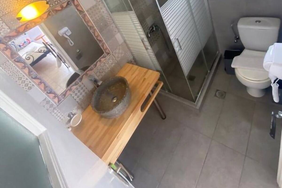A bathroom with a wooden vanity, a sink, a toilet, and a shower enclosure.