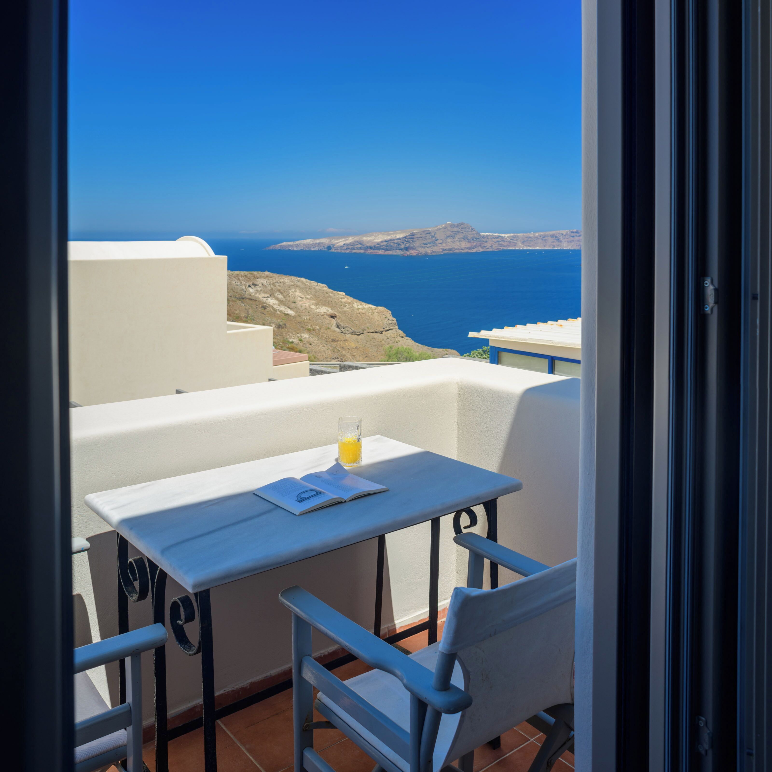 Un balcon avec une table et des chaises, donnant sur un paysage côtier.