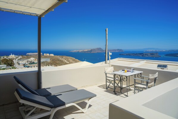 Un balcon avec vue sur la mer, une table avec des chaises et un fauteuil de relaxation.