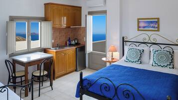 Un dormitorio con cama, escritorio y vista al mar.