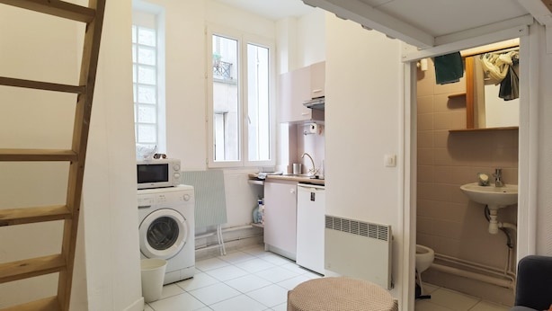 Une cuisine compacte équipée d’un lave-linge, d’un four à micro-ondes et d’un évier.