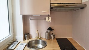 Une cuisine moderne dotée d’un évier en acier inoxydable, d’une cuisinière encastrée et d’une fenêtre laissant entrer la lumière naturelle.