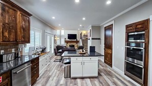 A modern kitchen with wooden cabinets, a central island, and built-in appliances. - Apollo Creed’s Powder Mountain Ski - Golf Retreat (Eden)