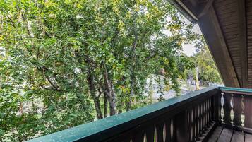 Un balcón de madera con vistas a un follaje verde y frondoso.