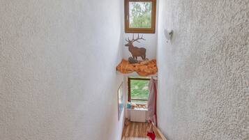 Eine enge Treppe mit einer Holzhandläufe, einem kleinen Fenster oben und einer an der Wand befestigten Dekoration mit Hirschmotiven.
