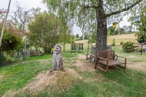 A park with a wooden bench, a sculpture, and a playground.