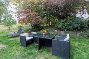 An outdoor seating area with a glass-top table and wicker chairs.