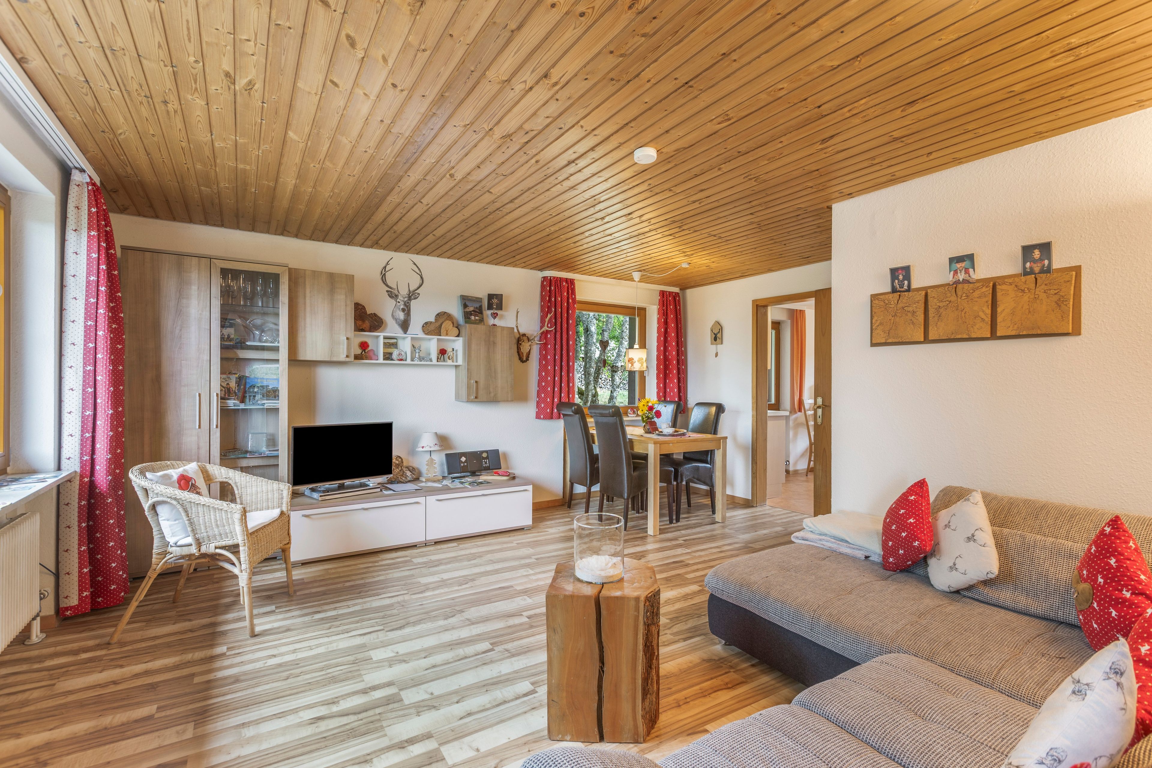 Uma sala de estar acolhedora com teto de madeira, um sofá, uma TV e um espaço de refeições.