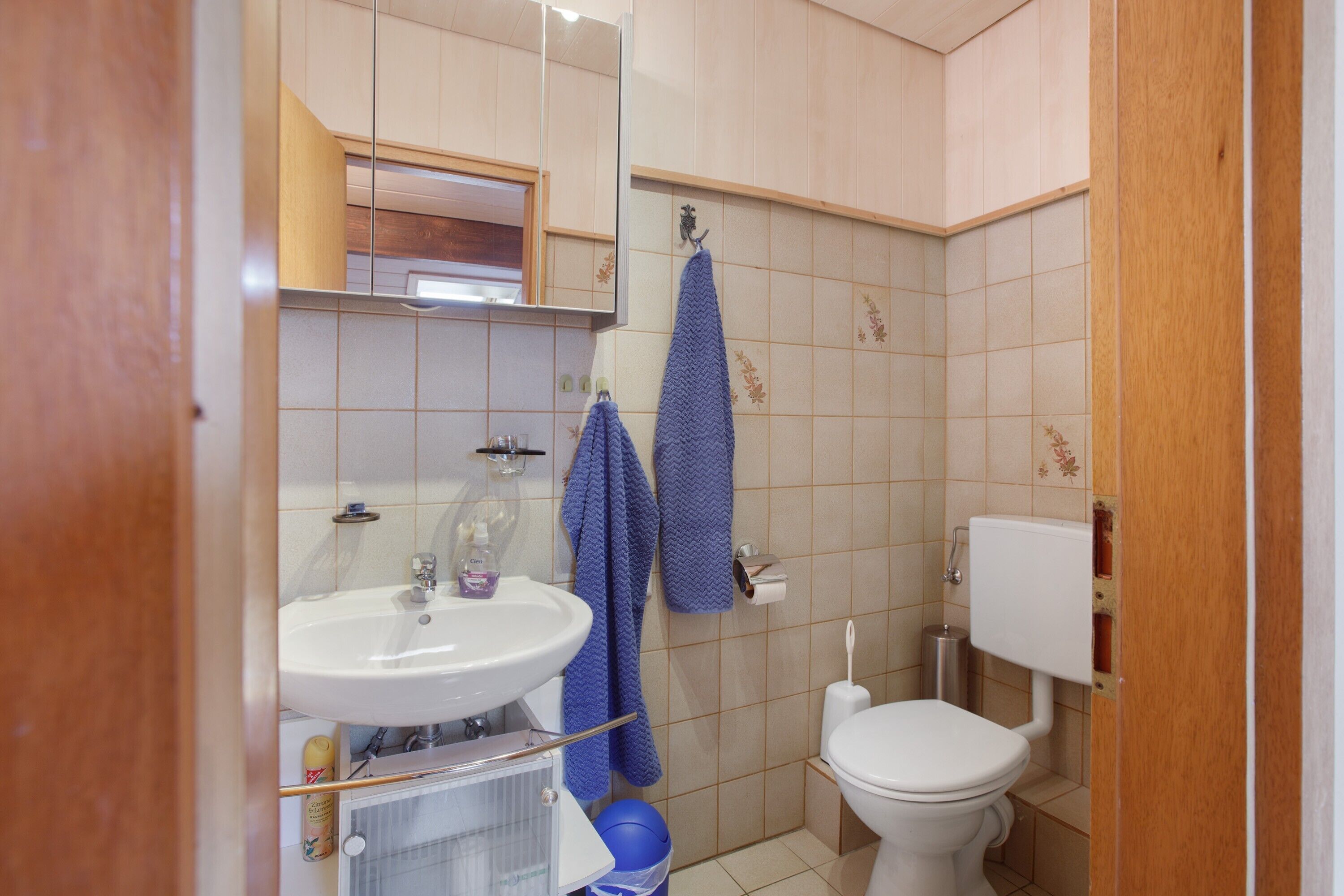 A bathroom with a sink, mirror, toilet, and blue towels.