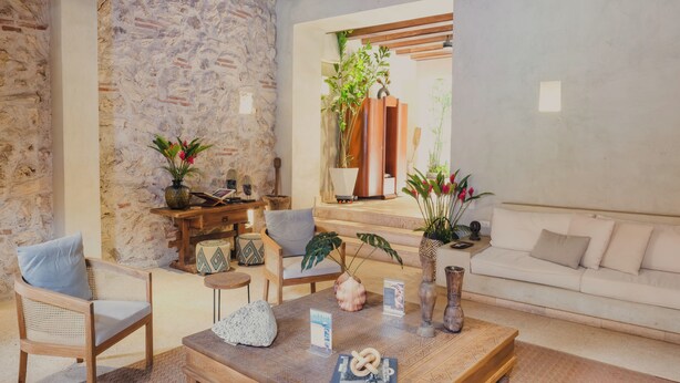 Una sala de estar acogedora con una pared de piedra, muebles de madera, un sofá y varios objetos decorativos.