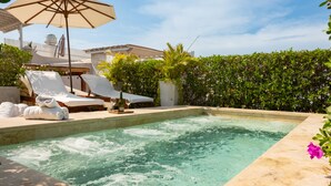 Zona de spa con jacuzzi, sillas de descanso y sombrillas.