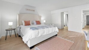 A modern bedroom with a large bed, two bedside tables, and a headboard with a 'dream' sign.