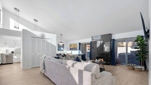 A modern living room with a sofa, a fireplace, and a view of the outdoors.