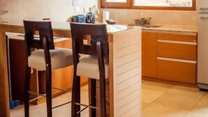 Cozinha compacta com ilha central, armários de madeira e janela que permite entrada de luz natural.