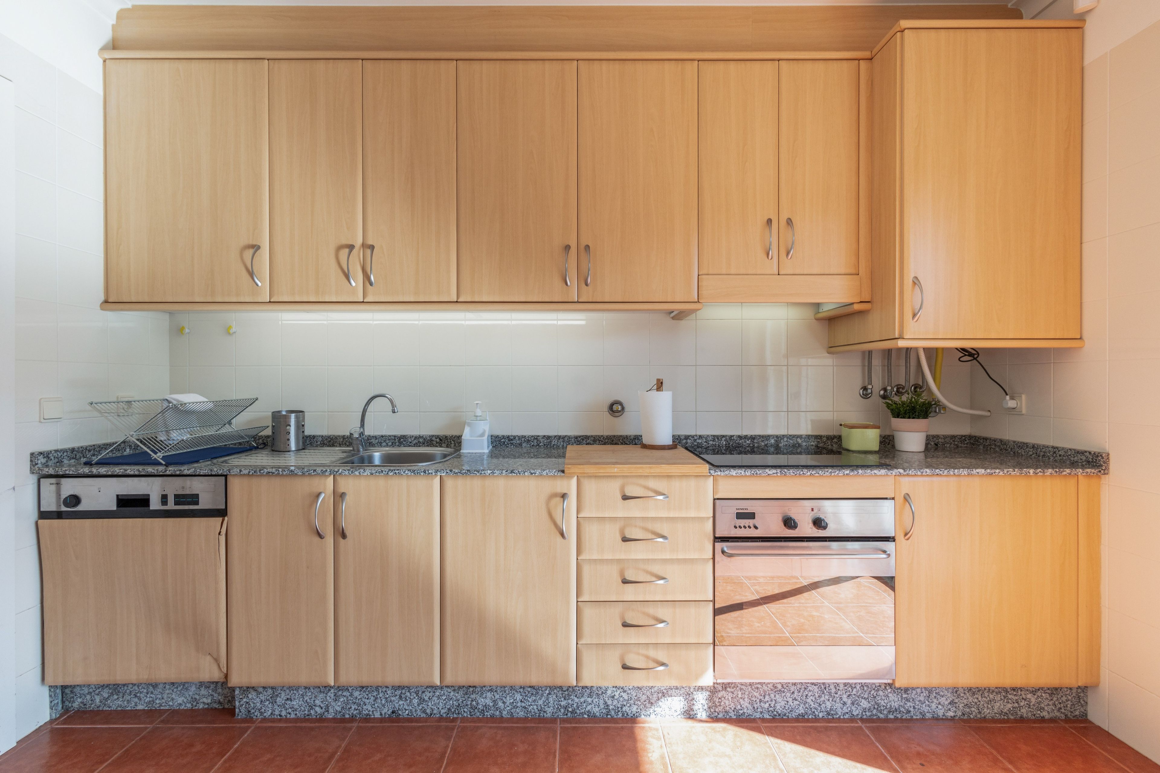 A kitchen with wooden cabinets, a granite countertop, a dishwasher, and an oven.