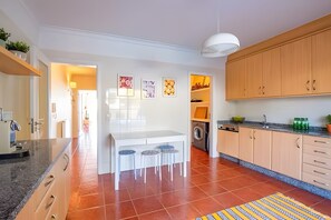 A modern kitchen with a central island, bar stools, wooden cabinets, and a washing machine. - Apartment 'Moledo With Private Pool A' with Sea View, Private Pool and Wi-Fi (Moledo)