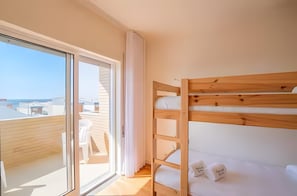 A bunk bed with white bedding, a sliding glass door to a balcony, and a white chair. - Apartment 'Moledo With Private Pool A' with Sea View, Private Pool and Wi-Fi (Moledo)
