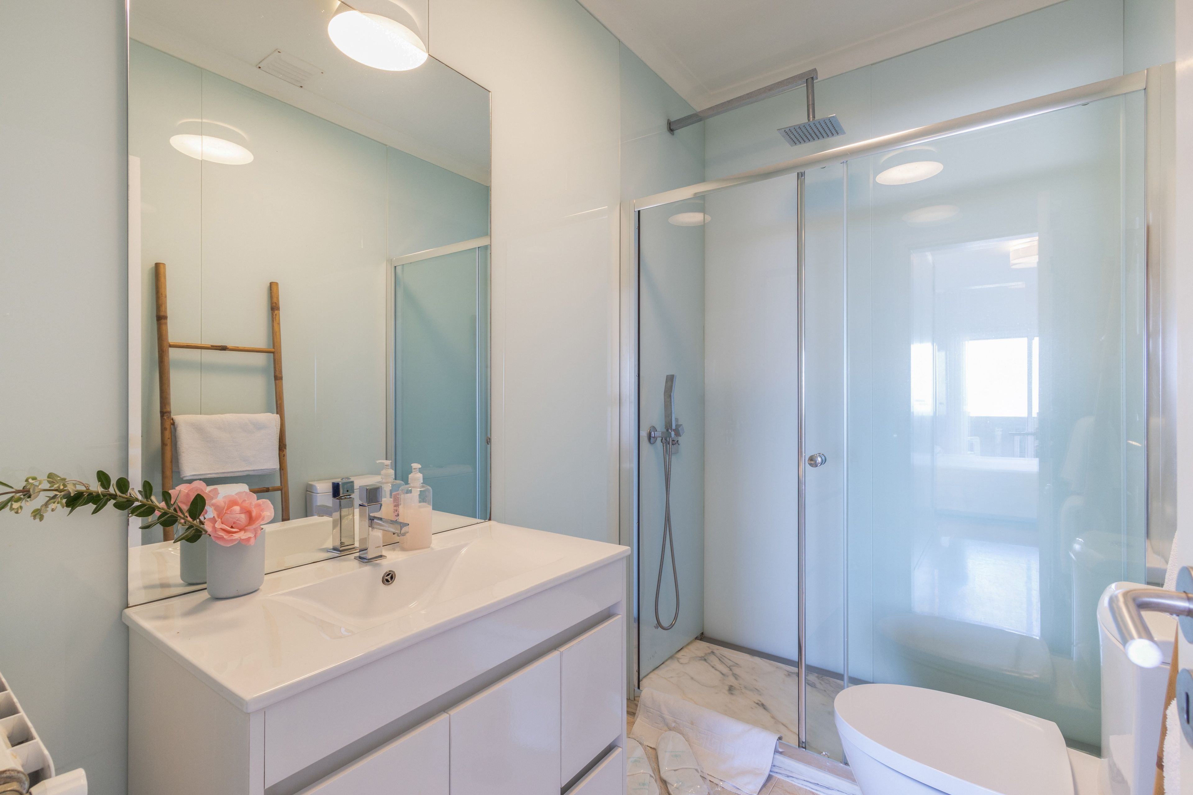 A modern bathroom with a glass shower enclosure, a white vanity with a mirror, and a toilet.