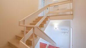 Una escalera con barandillas blancas y una pared blanca con una puerta en la parte superior.
