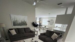Ein modernes Wohnzimmer mit zwei Sofas, einem Couchtisch und einem Deckenventilator.