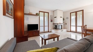 A living room with a sofa, a coffee table, a TV, and a fireplace. - Apartment 'Lago' with Mountain View, Private Terrace and Wi-Fi (Dongo)