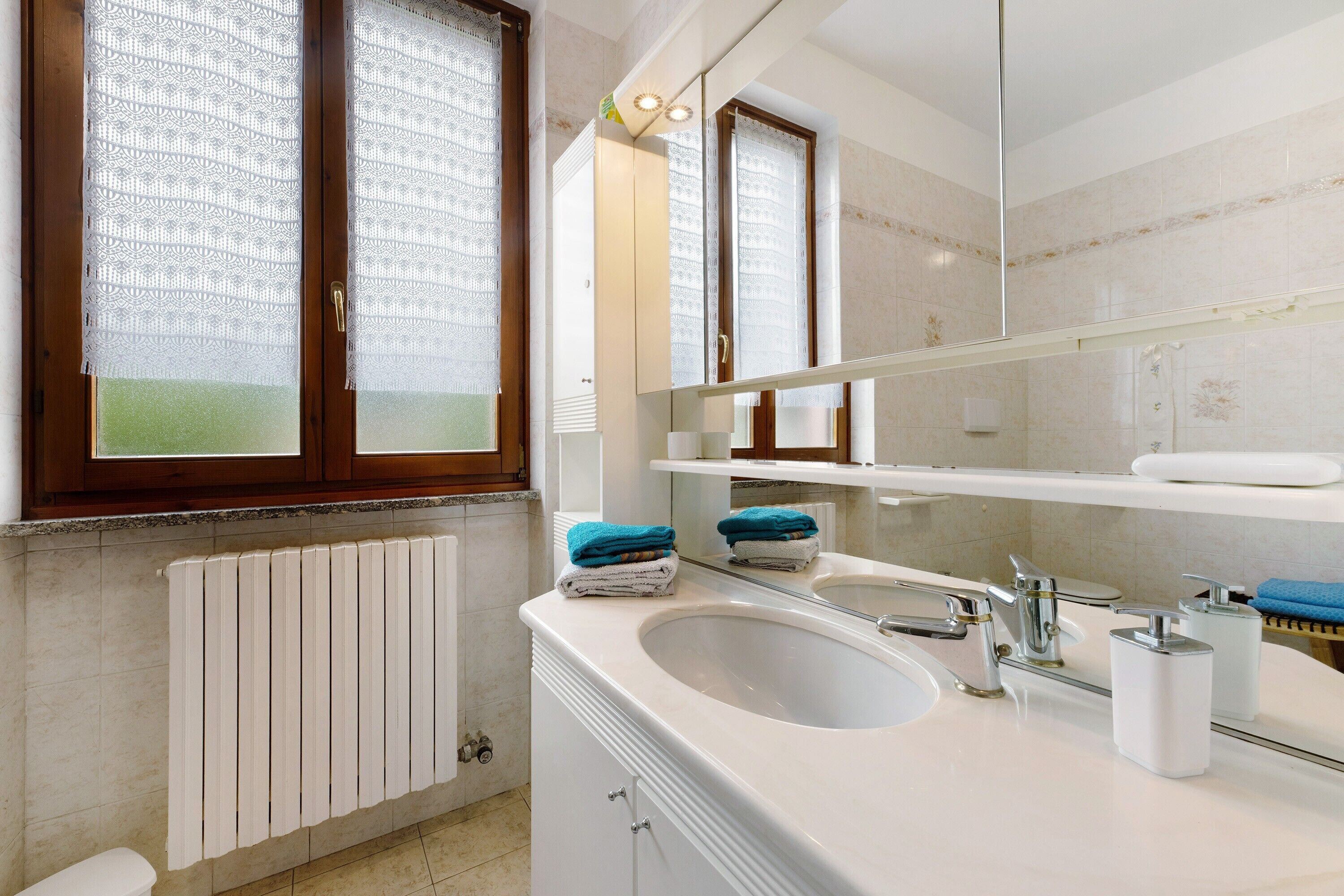 A bathroom with a white sink, mirror, and towel rack.