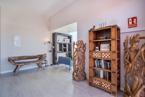 Una habitación con un banco de madera, una estantería llena de libros y una escultura decorativa de madera.