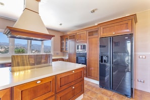 Una cocina con armarios de madera, una campana extractora de acero inoxidable, un horno doble y un refrigerador.