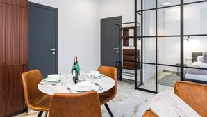 A modern dining area with a round table, brown chairs, and a bottle of champagne.
