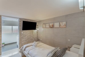 A modern bedroom with a bed, a TV mounted on the wall, and a sliding door leading to an outdoor area.
