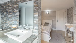 Un bany modern amb un mirall gran, un vàter blanc i una zona de dutxa.