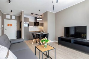 Ein modernes Wohnzimmer mit einer Couch, einem Fernseher und einem Essbereich mit Stühlen und einem Tisch.
