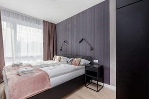 Une chambre à coucher moderne avec un lit, des tables de chevet et une armoire.