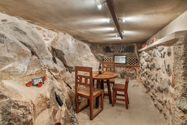 A rustic dining area with stone walls, wooden furniture, and a sign reading 'Villa Bandama Golf'.