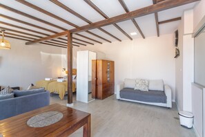 A modern living room with a wooden ceiling, a sofa, a dining table, and a cabinet.