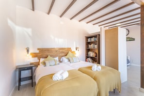 A double bed with two side tables, a wooden headboard, a bookshelf, and a clock on the wall.