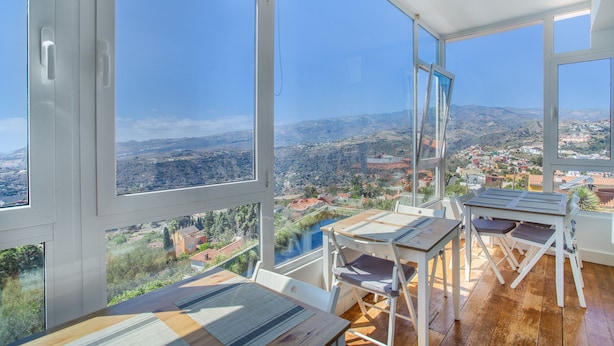 A room with large windows, wooden furniture, and a view of a valley. - 'Villa bandama golf Galdar-06' with sea views, Wi-Fi and air conditioning (santa brigida)