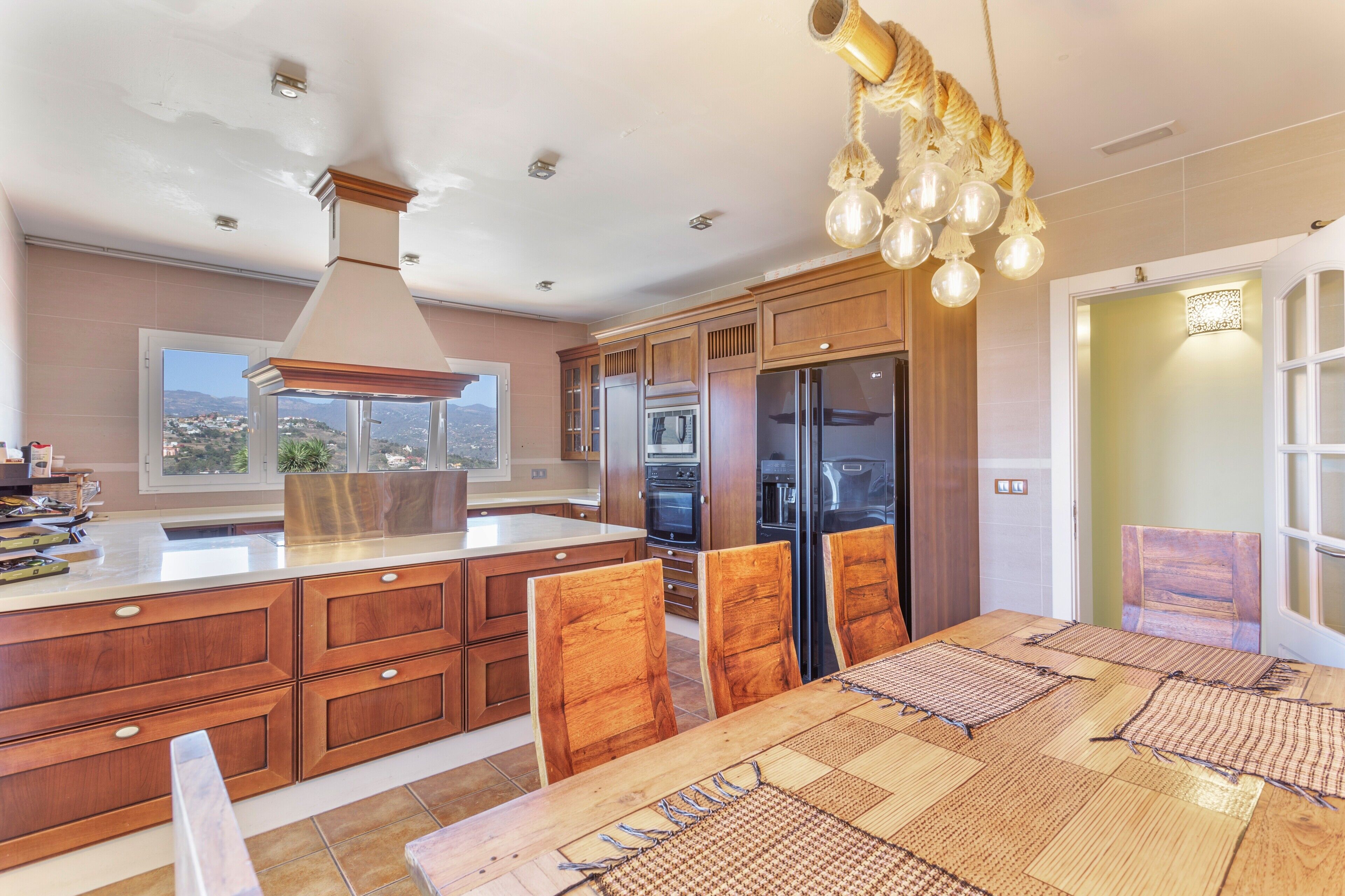 A modern kitchen with wooden cabinets, a central island, and a dining area with a table and chairs.
