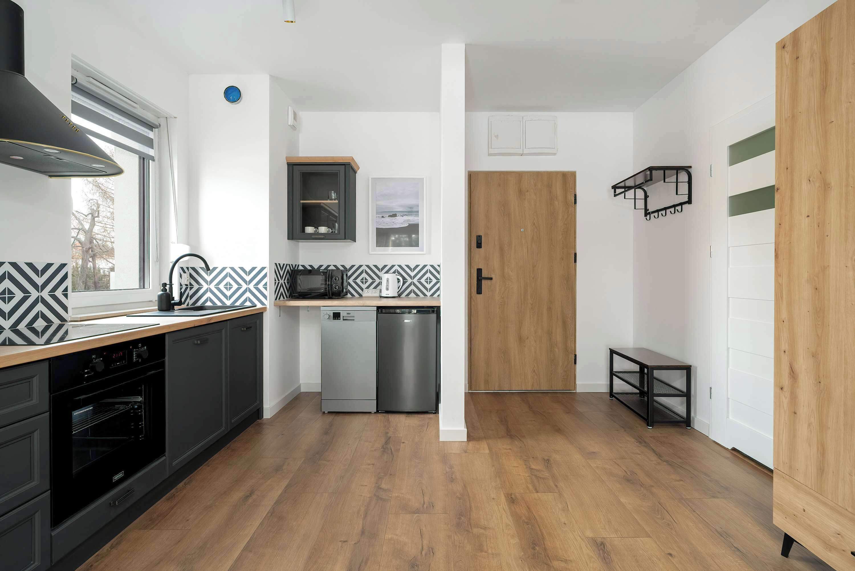 Una cucina moderna con mobili grigi, forno integrato, lavastoviglie e microonde.