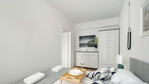 A modern hotel room with a bed, a bedside table with a lamp, a tray with a plate and a glass, and a painting on the wall. - Stylish Apartment in Poznan | Terrace | Parking (Poznań)