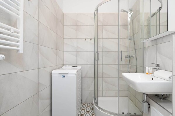 A modern bathroom with a glass-enclosed shower, a white sink, and a toilet.