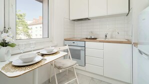 A modern kitchen with white cabinetry, a wooden countertop, and a built-in oven. - Bright Studio | A Place to Work and Close to the Fair (Poznań)