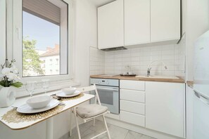 Een koelkast, een oven, een kookplaat, kookgerei, borden en bestek