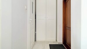 A hallway with a white wardrobe, a wooden door, and a black doormat. - Bright Studio | A Place to Work and Close to the Fair (Poznań)