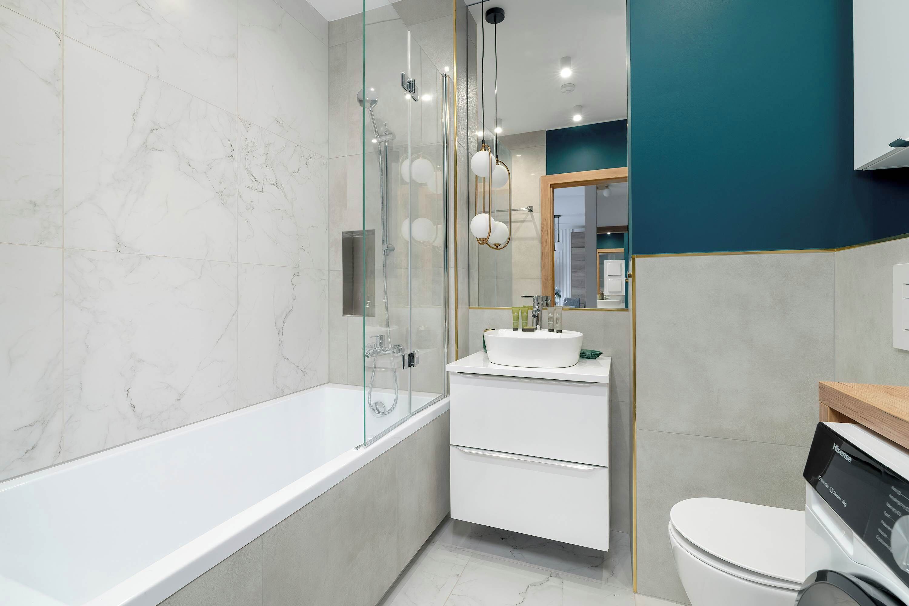 Un baño moderno con ducha envuelta en vidrio, un lavamanos blanco y un inodoro.